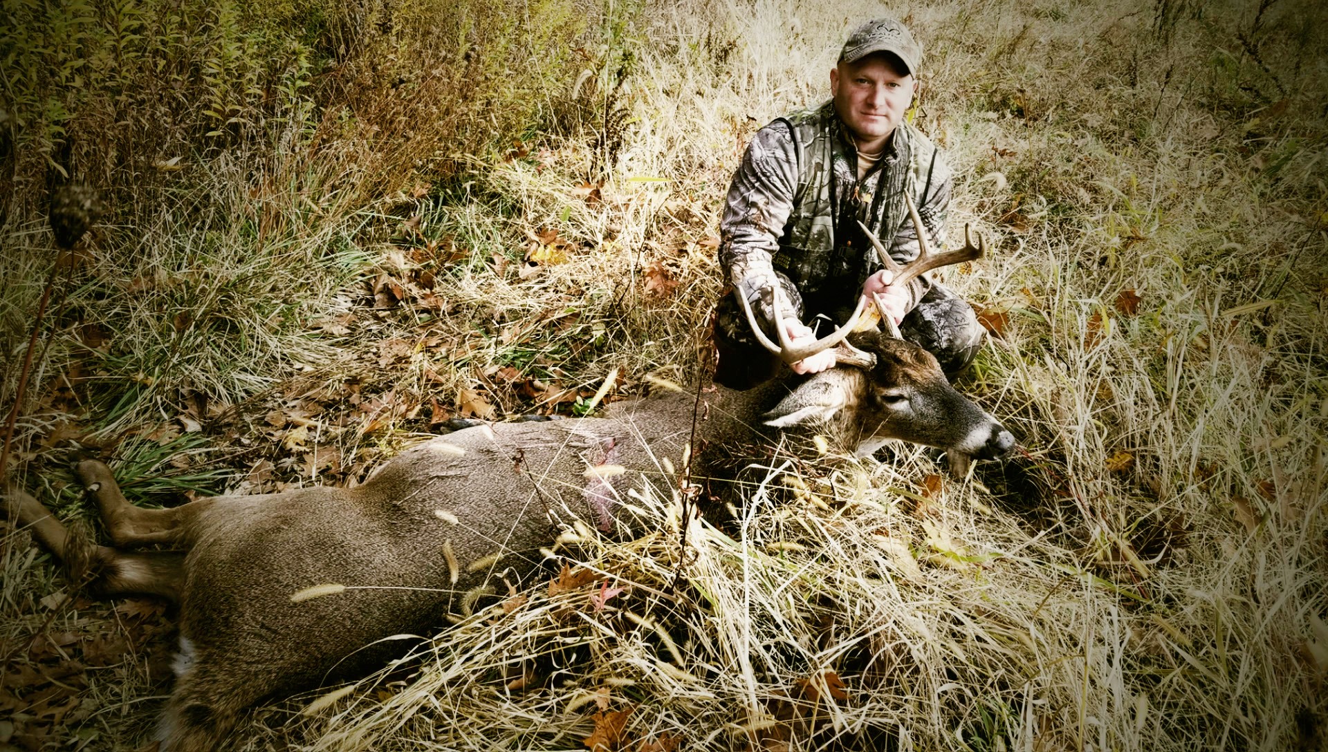 Anthony DelVecchio with a mature whitetail buck in autumn grass